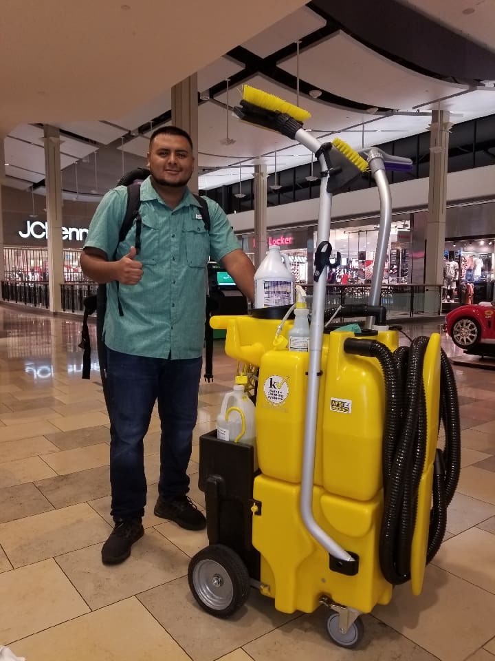 a man standing next to a yellow cleaning cart